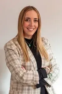 Flores blancas y plumosas en un jarrón con una mariposa posada en un tallo, contra una pared cálida.