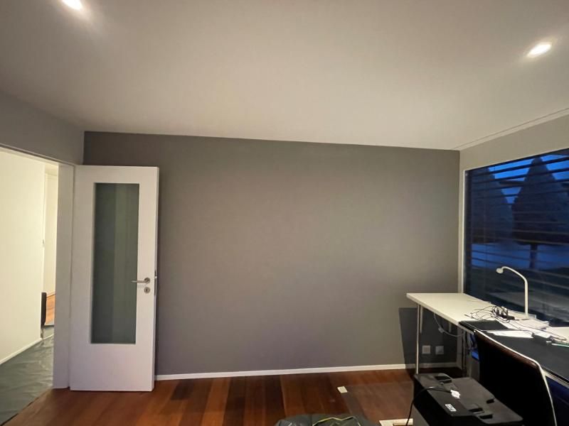 Un salon avec un mur gris et une porte blanche