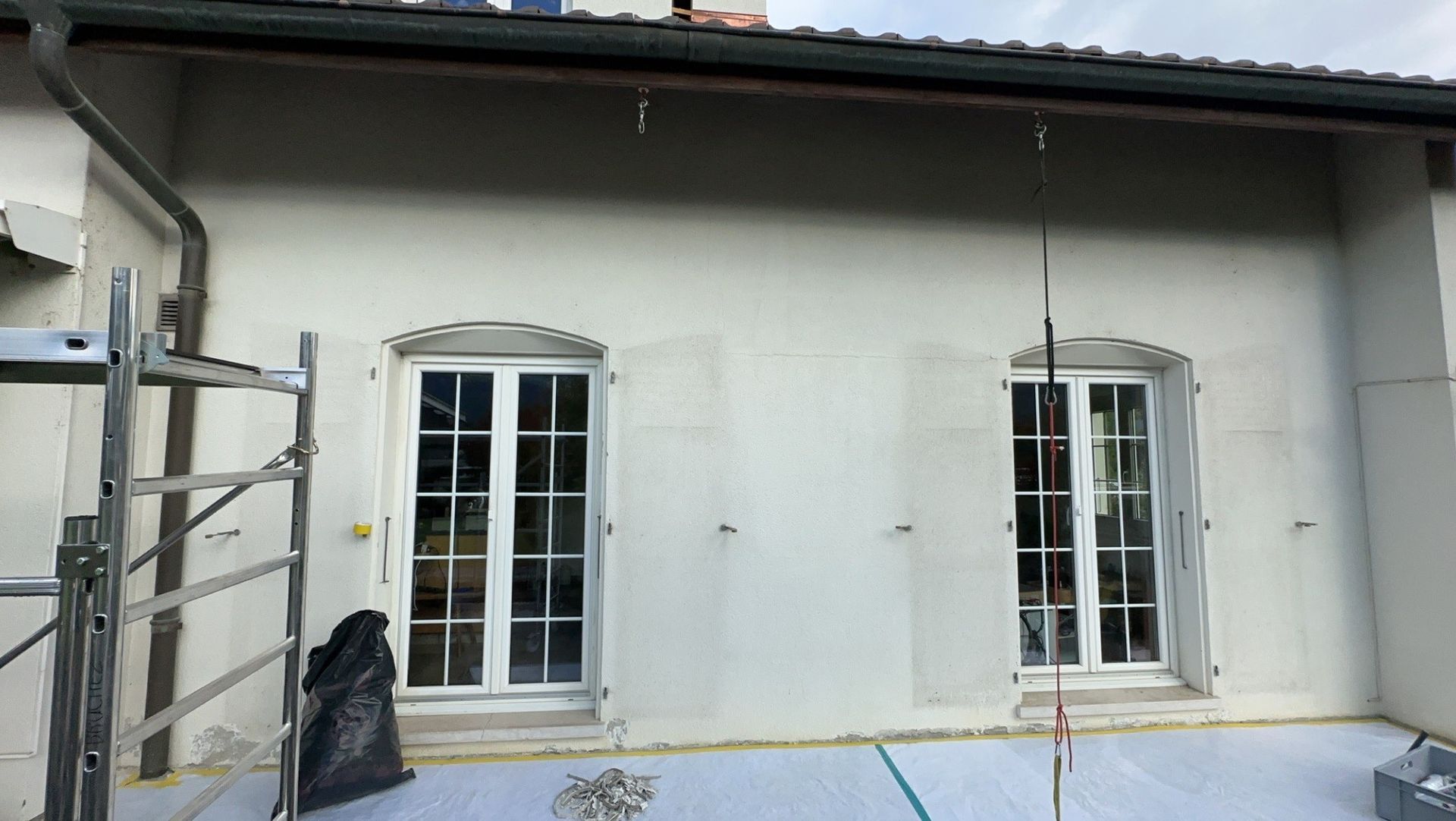 Une maison blanche avec deux fenêtres et un échafaudage devant avant rénovation