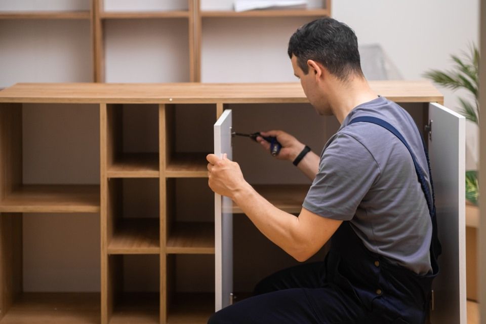 Eine Person justiert die Scharniere eines Schranks