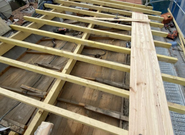 Une structure en bois est en train d'être construite au sommet d'un bâtiment.