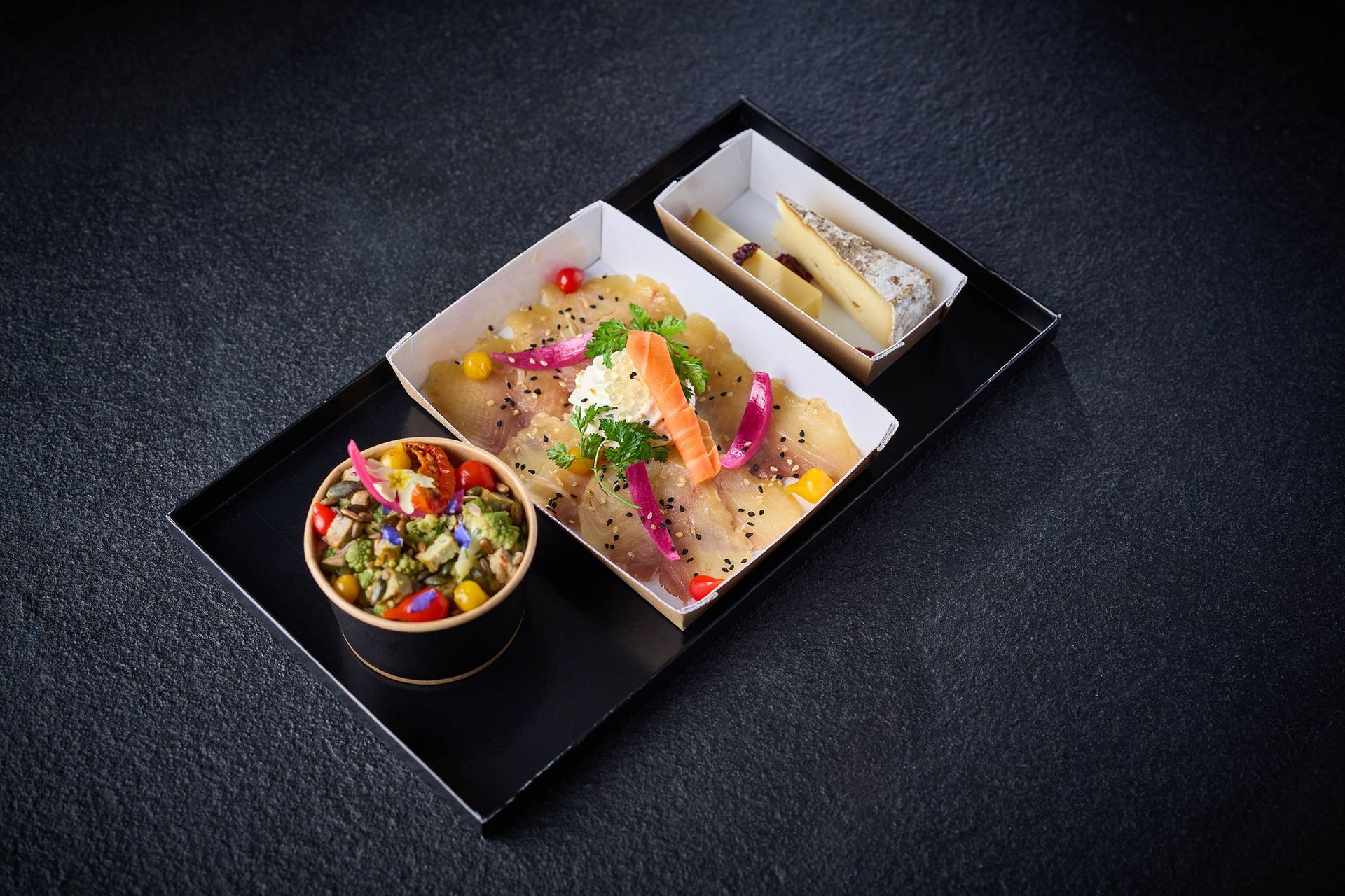 Repas complet présentés sur un plateau noir, entrée (salade composée), plat et fromage