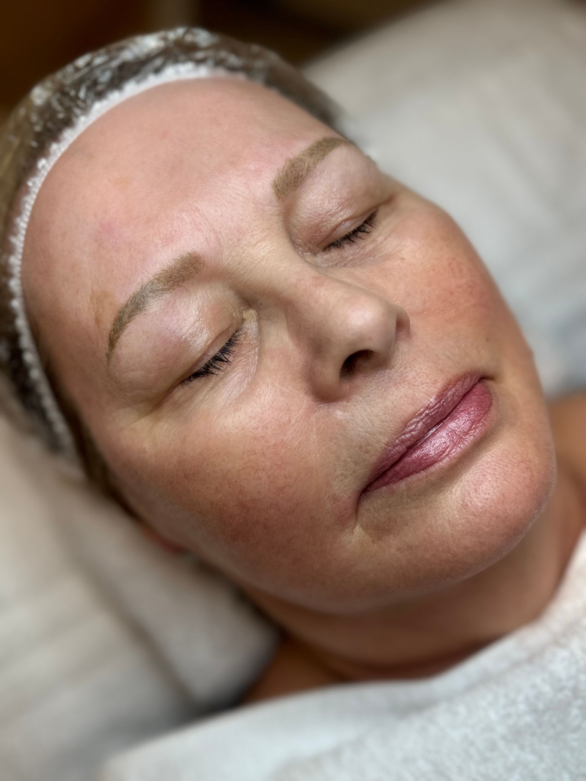 Nahaufnahme einer entspannten Person mit Gesichtsmaske, die in einer Spa-Umgebung zurückgelehnt liegt