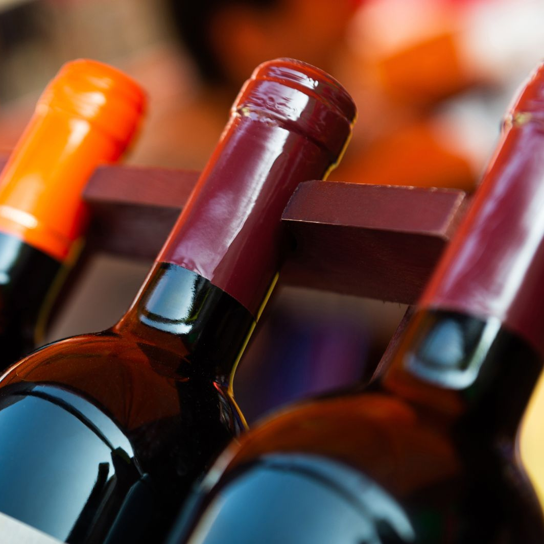 Des bouteilles de vin dans une caisse en bois. Bouteilles rouge foncé et orange.