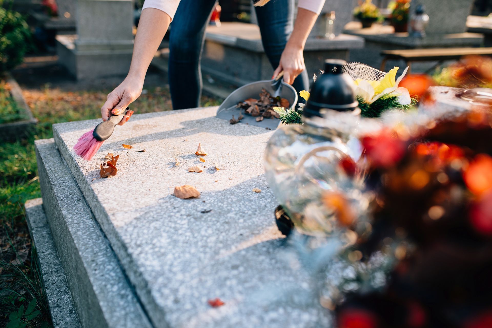 Une personne ramasse les feuilles mortes sur un caveau
