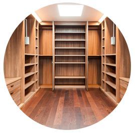 Vestidor vacío con estantes de madera, barras y un cálido suelo de madera bajo una claraboya.