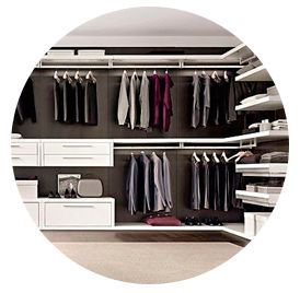Vestidor con espacio para colgar ropa, cajones, estantes y prendas dobladas en un moderno diseño en blanco y madera oscura.