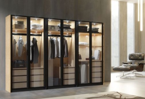 Vestidor moderno con puertas de cristal, perchero y silla en una habitación luminosa.