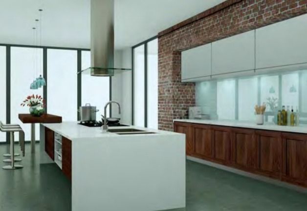 Cocina moderna con isla blanca, pared decorativa de ladrillo visto, grandes ventanales y armarios de madera.