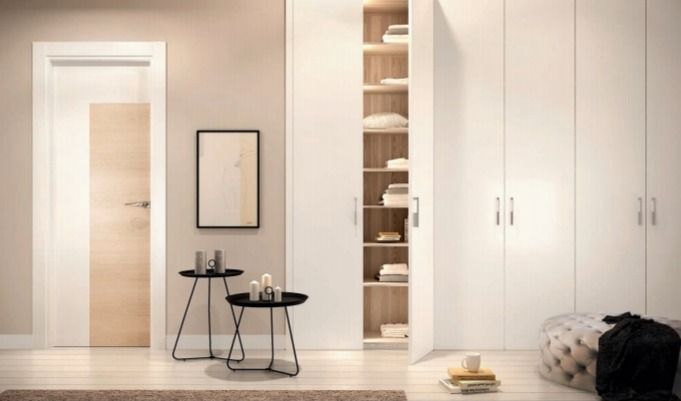 Pasillo minimalista con puertas blancas, una pequeña mesa auxiliar negra, espejo y estanterías empotradas.