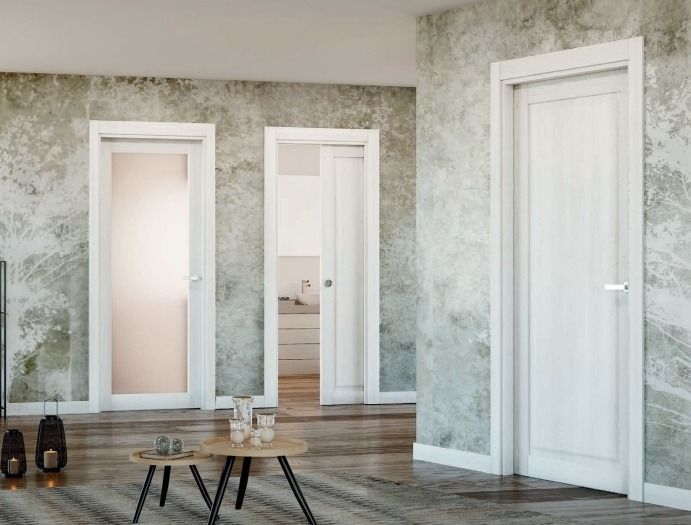 Interior moderno y vacío con tres puertas blancas, paredes con estampados claros y una pequeña mesa de centro sobre suelo de madera.