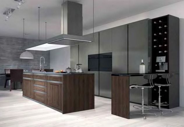 Cocina moderna gris con isla de madera oscura, campana extractora de acero inoxidable y cafetera integrada.