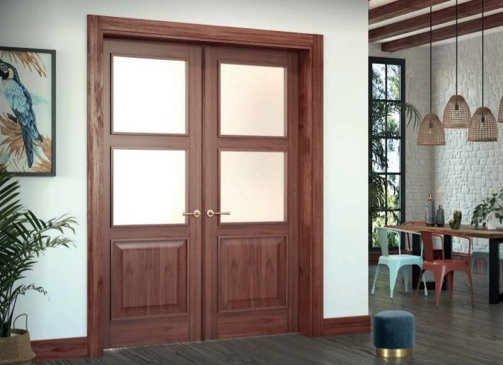 Puertas dobles de madera con cristal en un interior luminoso y moderno con plantas y un comedor visible junto a ellas.