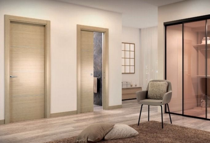 Sala de estar minimalista con paredes beige, puertas corredizas de madera y cristal, silla, cojín y mampara transparente.