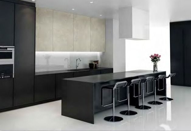 Cocina moderna en blanco y negro con isla, taburetes de bar y electrodomésticos integrados.