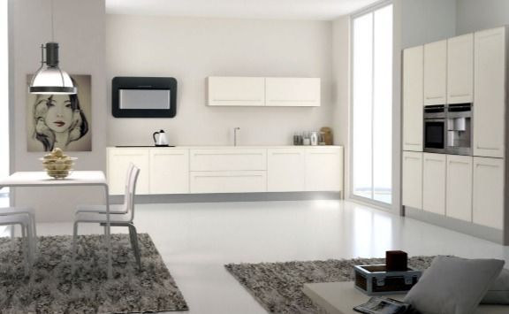 Moderno salón-comedor blanco con elegantes armarios, lámpara colgante, alfombras grises y grandes ventanales.