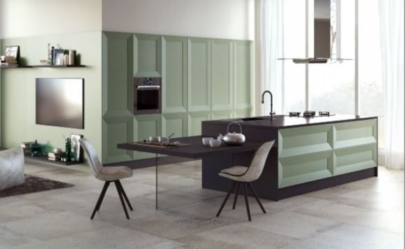 Cocina moderna con gabinetes verde menta, isla oscura y dos taburetes en un luminoso espacio abierto.