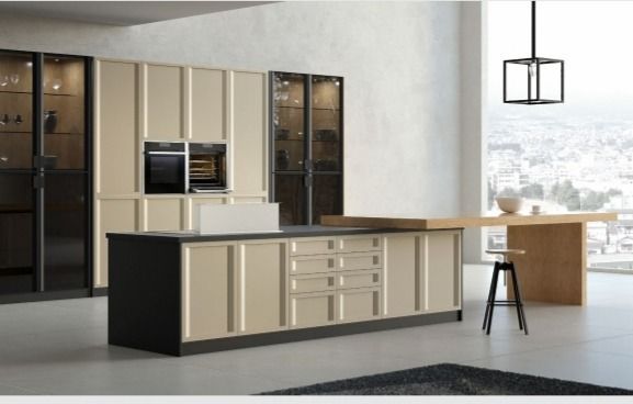 Cocina moderna con isla beige, armarios negros y grandes ventanales con vistas a una luminosa ciudad.
