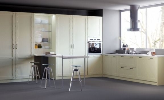 Cocina moderna con armarios color crema, isla central, taburetes y fregadero junto a una ventana luminosa.
