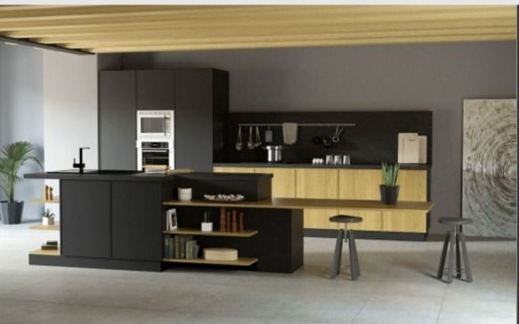 Cocina moderna con gabinetes negros, detalles en madera clara, isla y mesa de comedor en un espacio abierto y luminoso.