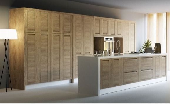 Cocina moderna con gabinetes de madera clara, encimeras blancas y una isla central bajo iluminación cálida.