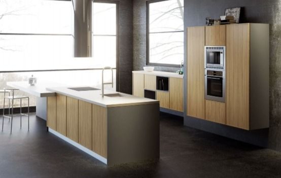 Cocina moderna con armarios de madera clara, una gran isla y horno empotrado junto a ventanas luminosas.