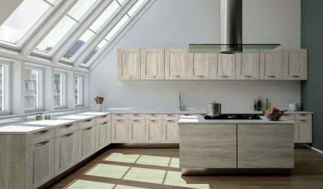 Cocina moderna y luminosa con tragaluces, gabinetes blancos y una isla central.