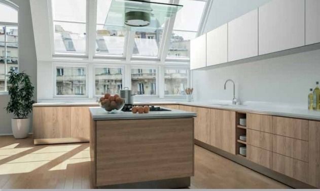 Cocina moderna y luminosa con armarios de madera, isla central y grandes ventanales con vistas a la vegetación.