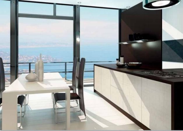 Cocina y comedor modernos con vistas al mar a través de grandes ventanales.