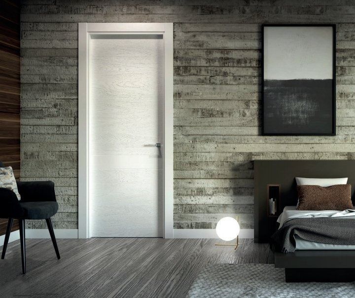 Dormitorio moderno con puerta esmerilada, cama, silla y lámpara de pie con luz tenue.