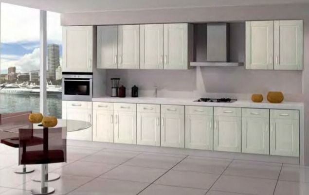Cocina moderna blanca con isla, horno empotrado, grandes ventanales y vistas a la ciudad.