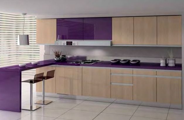 Cocina moderna con detalles en color púrpura, gabinetes de madera clara, encimera negra y una pequeña barra para desayunar.