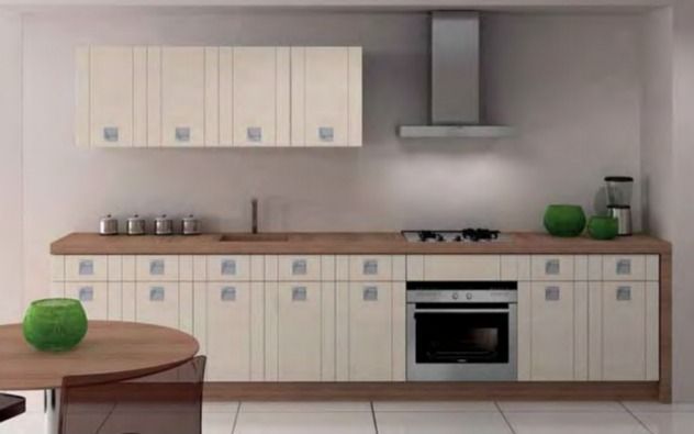 Cocina moderna con armarios claros, encimeras de madera, estufa, campana extractora y una mesa redonda con un cuenco verde.