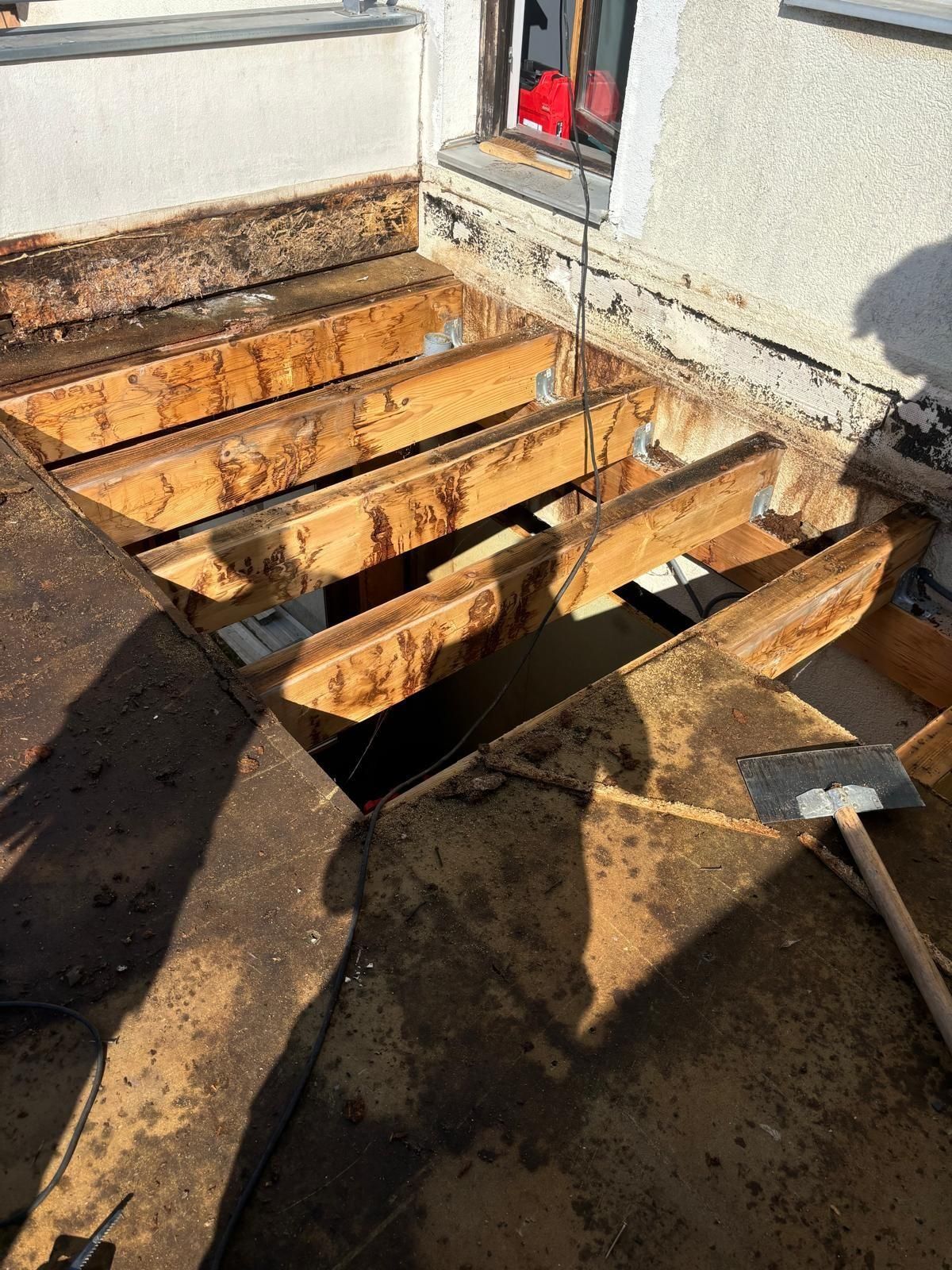 Terrasse sur le toit en construction : poutres en bois apparentes, matériau de toiture détérioré, extérieur du bâtiment, lumière du jour.