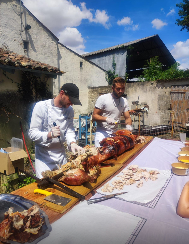 Un cuisinier qui découpe le cochon à la broche pour préparer le repas des clients