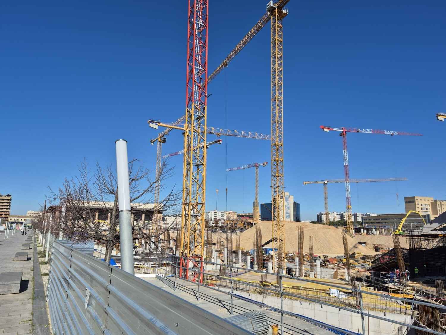 Obreros de la construcción en una obra con andamios y un camión hormigonera delante.