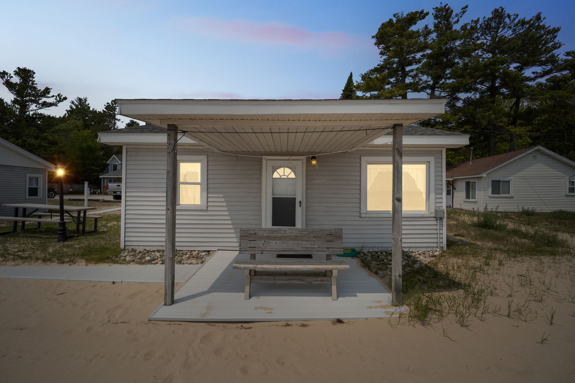 A small white house is sitting on top of a sandy beach.