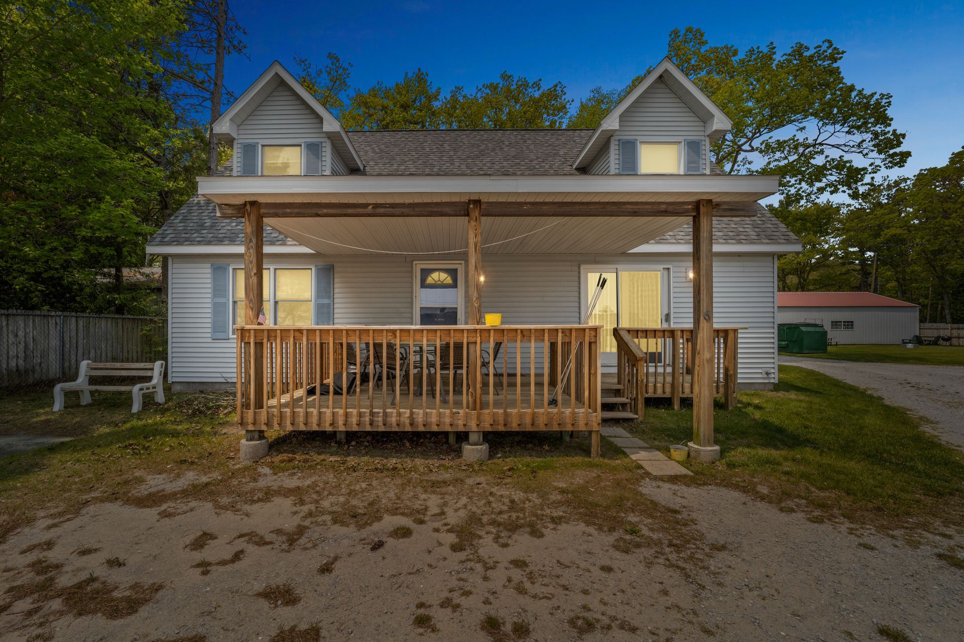 A white house with a porch and a flag in front of it.