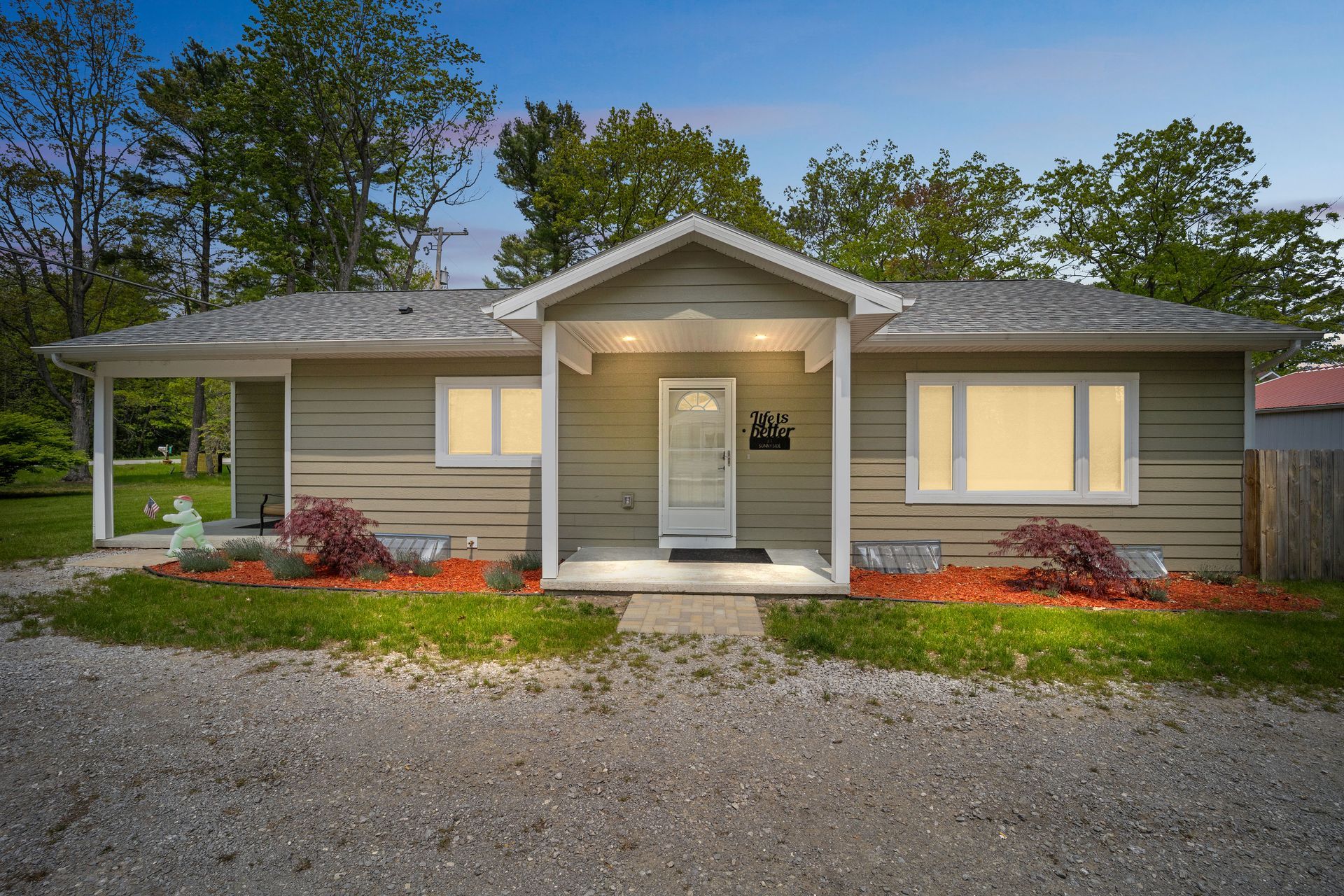A small house with a porch and a bench in front of it.