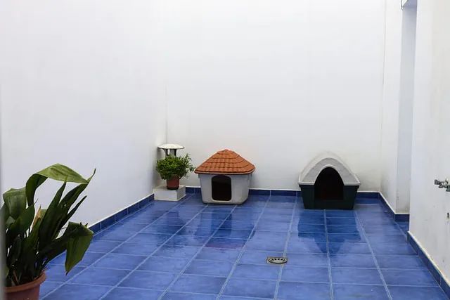 Una caseta para perros está sobre un suelo de baldosas azules.