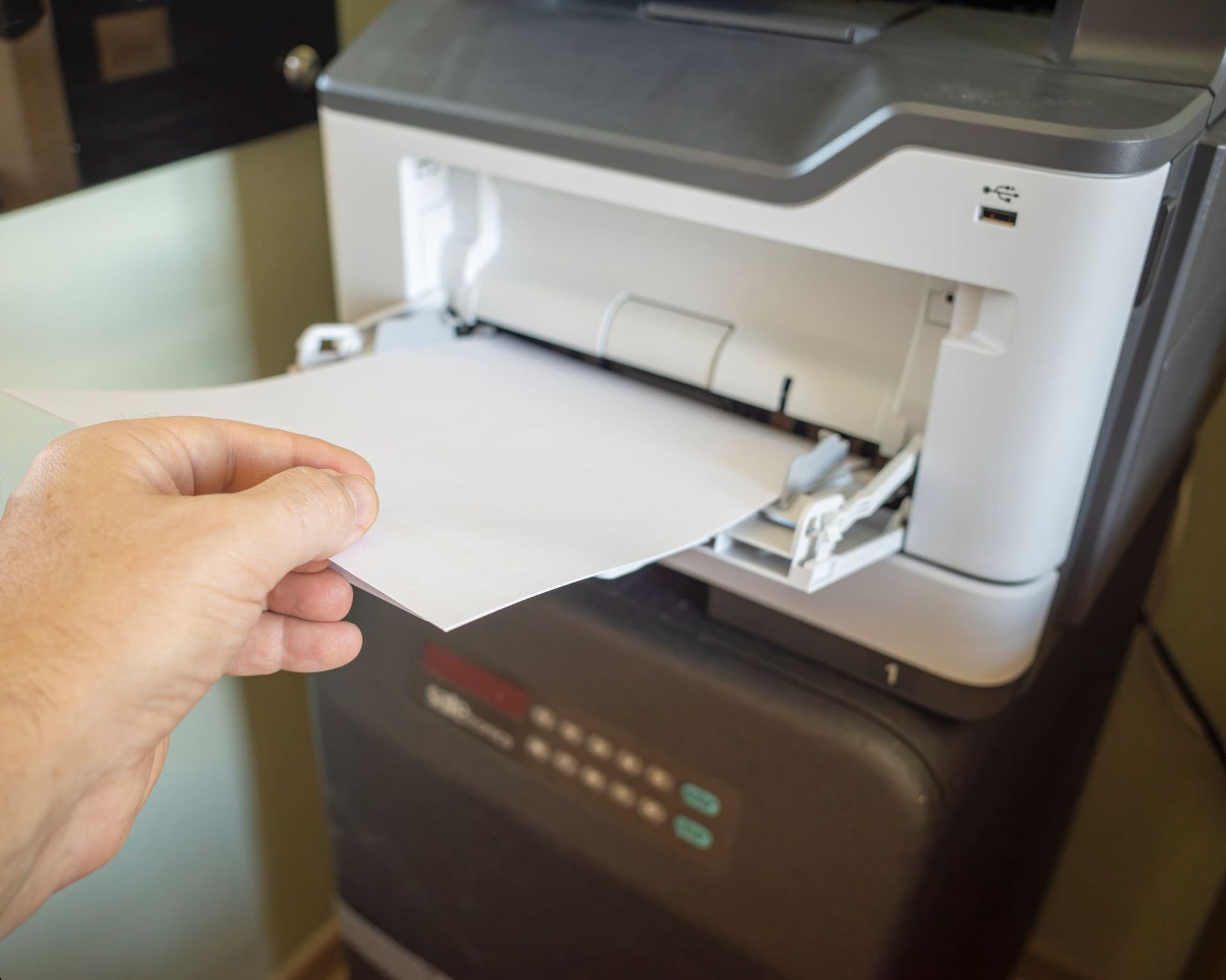 Una persona sostiene un trozo de papel delante de una impresora.