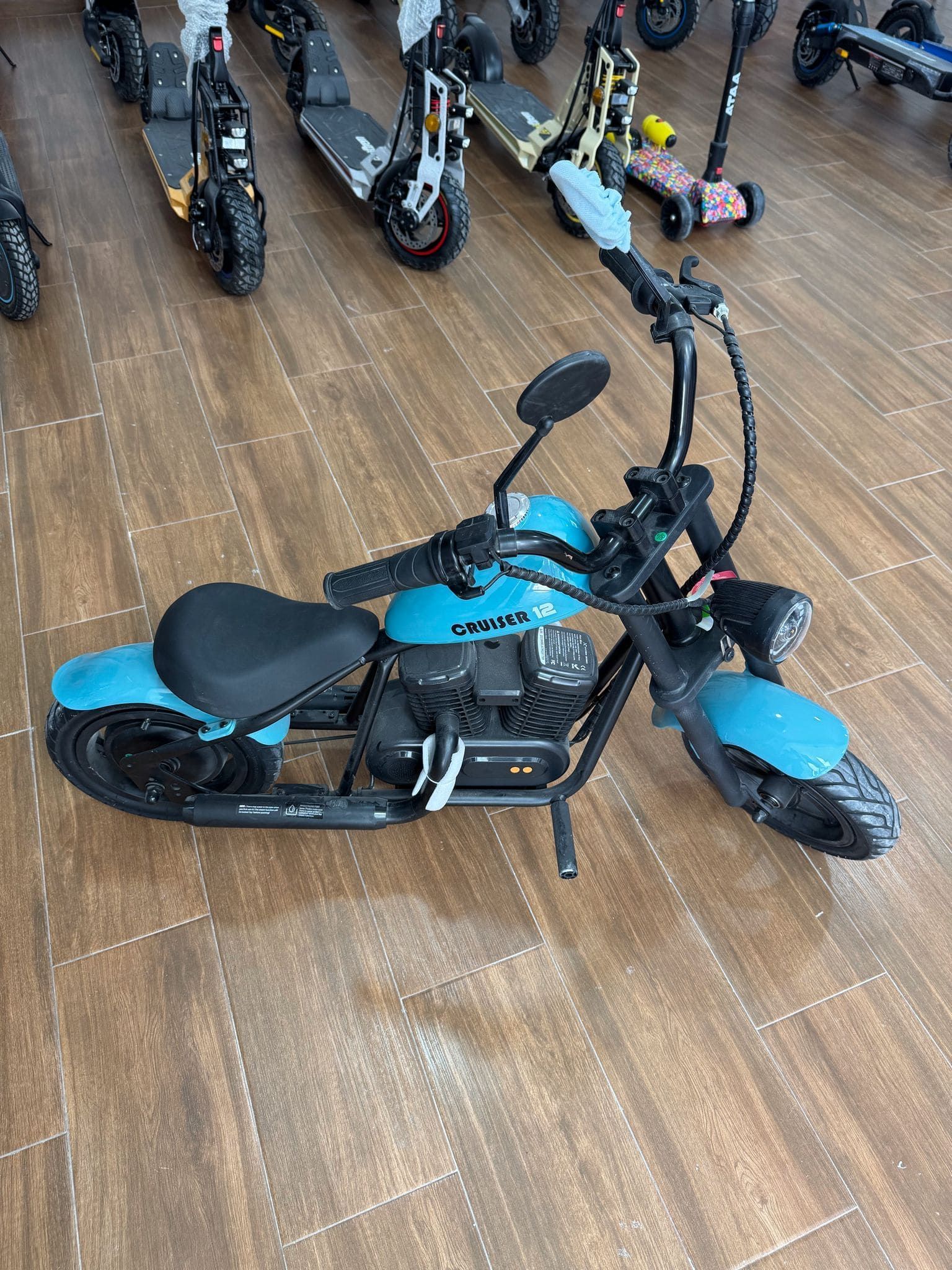 Una motocicleta azul y negra está estacionada sobre un piso de madera en una sala de exposición.