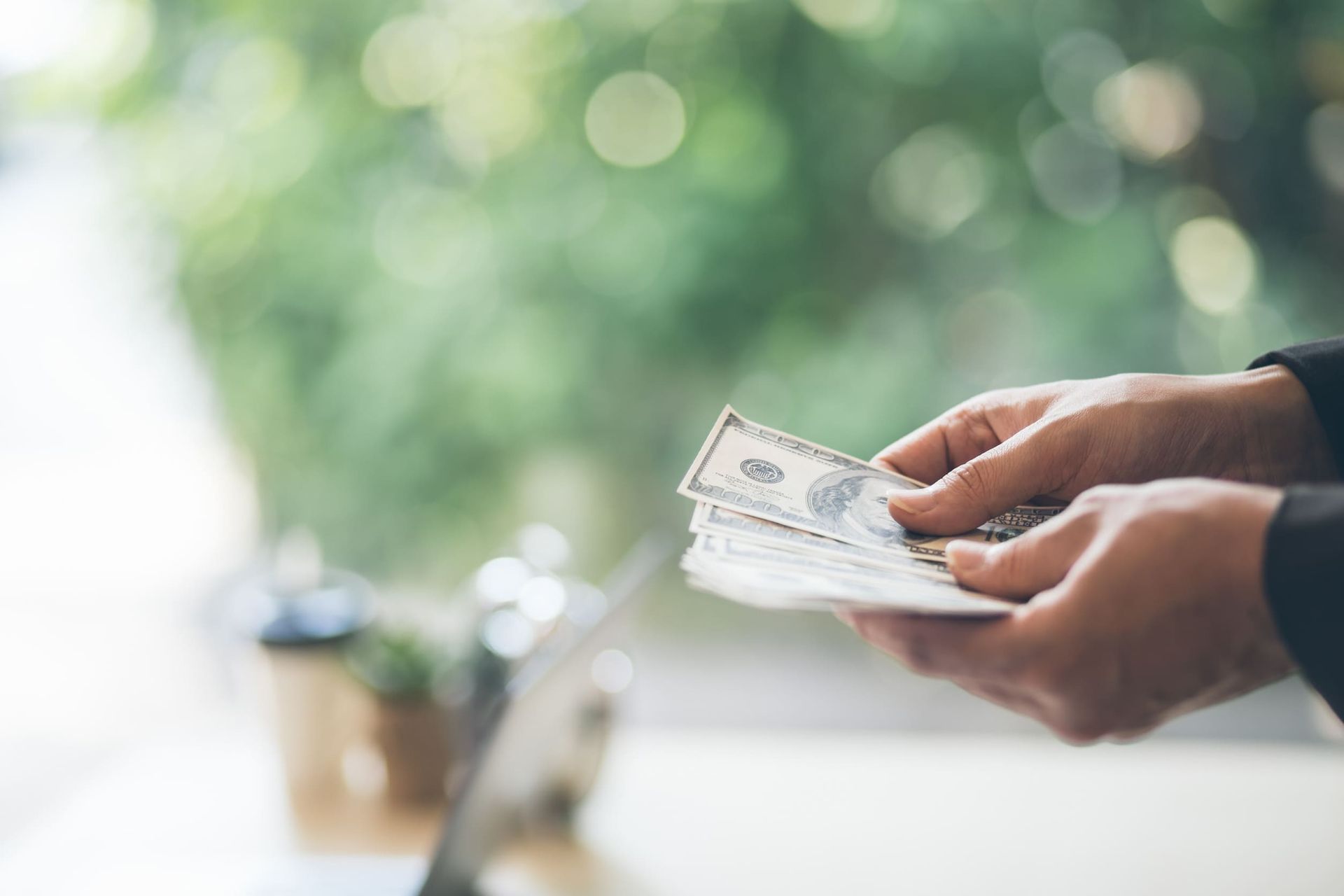 Una persona sostiene un montón de dinero en sus manos.