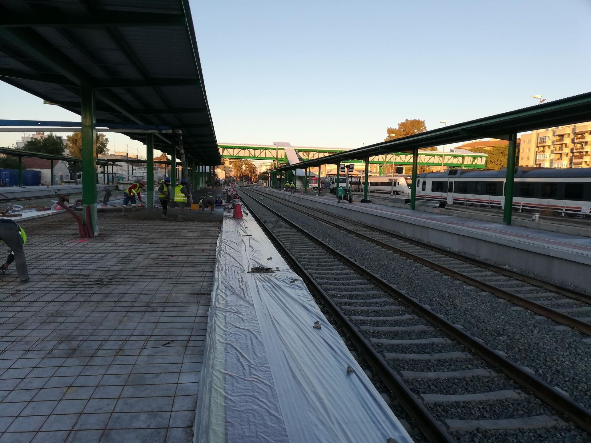 Una estación de tren con techo verde y vías de tren