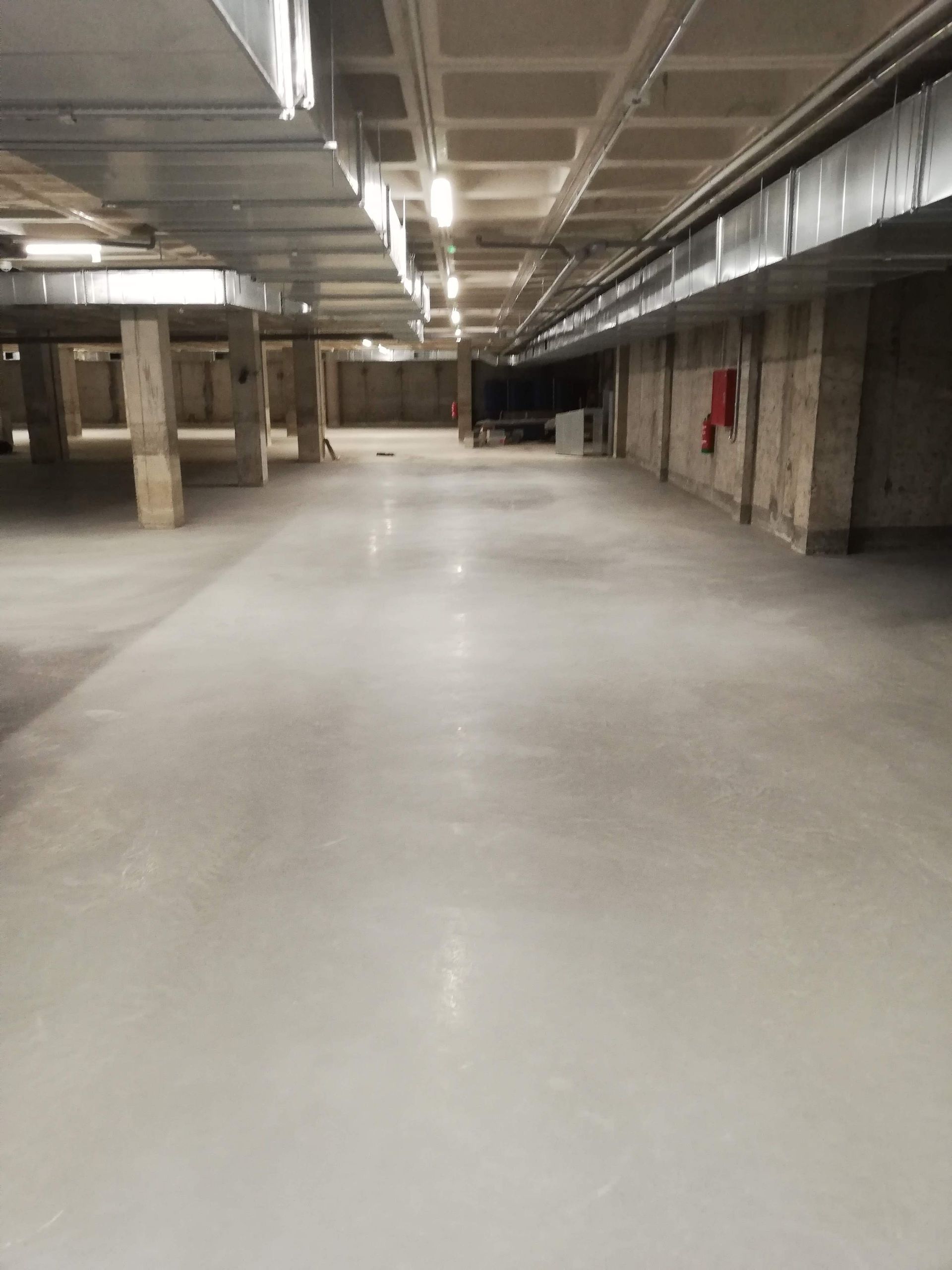 Un gran aparcamiento subterráneo vacío con suelo blanco.