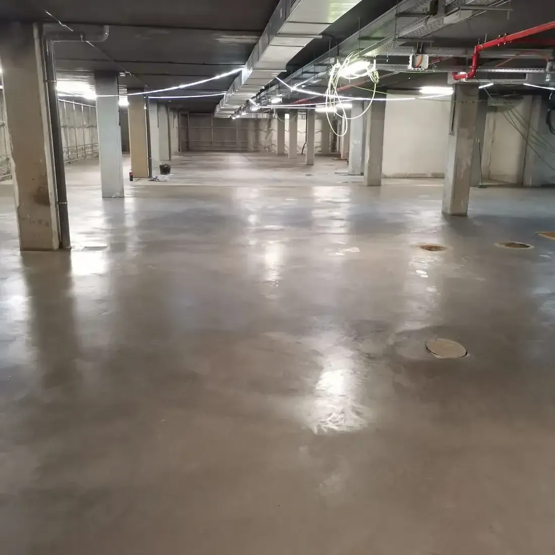 Un gran estacionamiento subterráneo vacío con pisos y columnas de concreto.