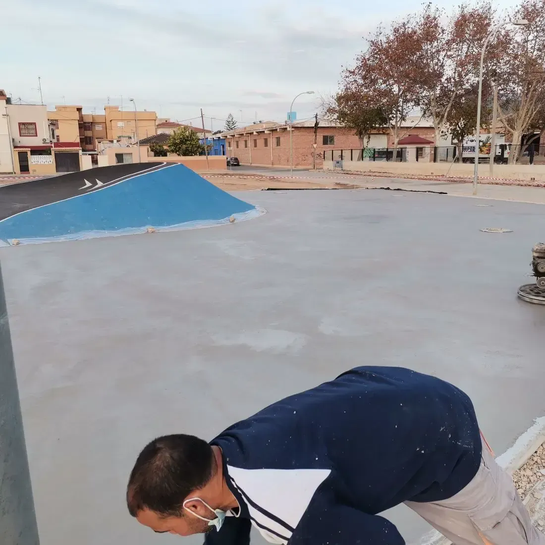 Un hombre que lleva una máscara está arrodillado sobre una superficie de hormigón.