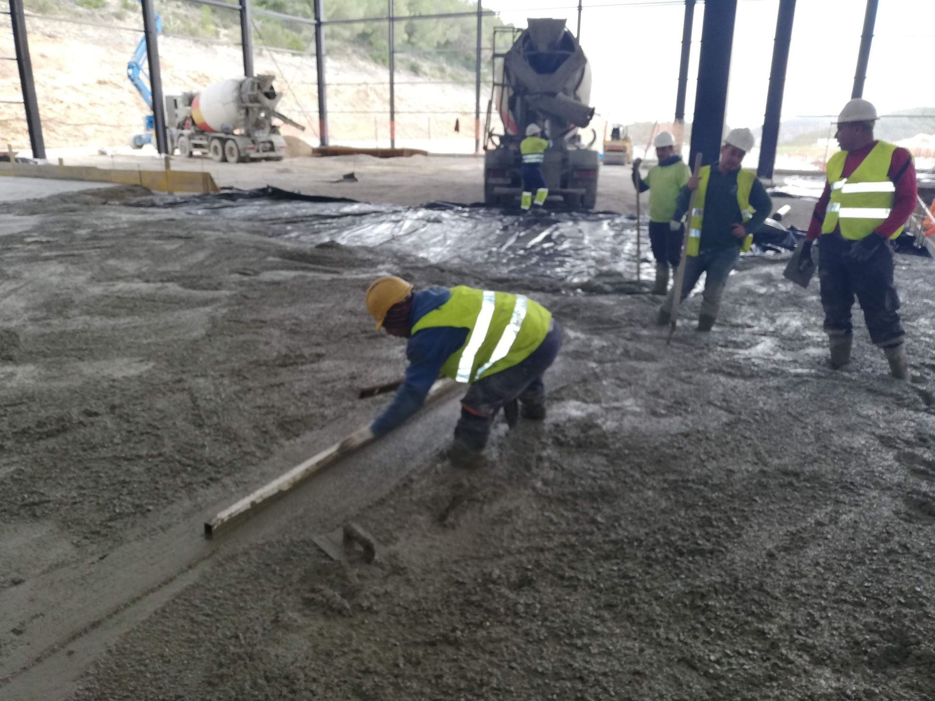 Un grupo de trabajadores de la construcción está trabajando en un piso de concreto.