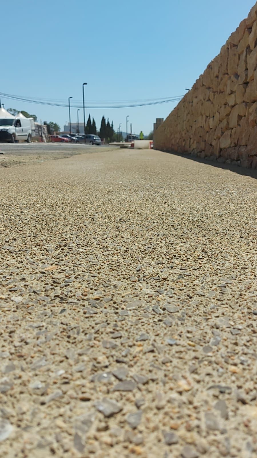 Un camino de grava con un muro de piedra al fondo