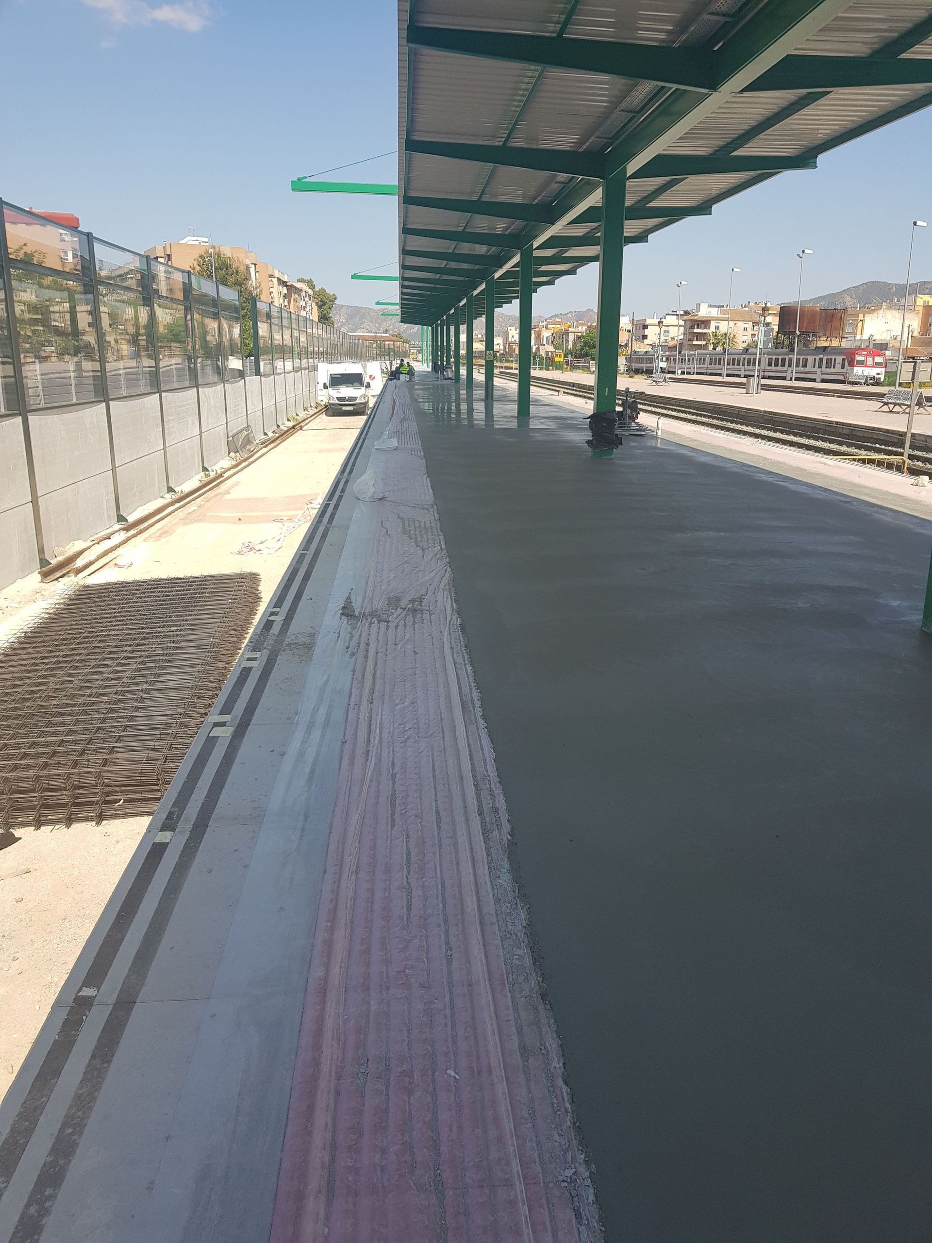 Una estación de tren con barandilla de madera y techo verde.